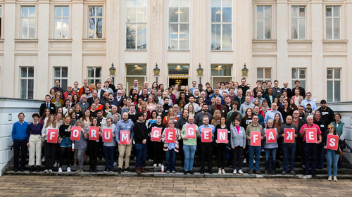 Die Teilnehmer:innen des Bürgerrates zum "Forum gegen Fakes" haben sich für ein Gruppenfoto auf den Stufen vor dem Kronprinzenpalais in Berlin aufgestellt. Einige von ihnen halten Buchstabentafeln in der Hand, die den Schriftzug "Forum gegen Fakes" ergeben.